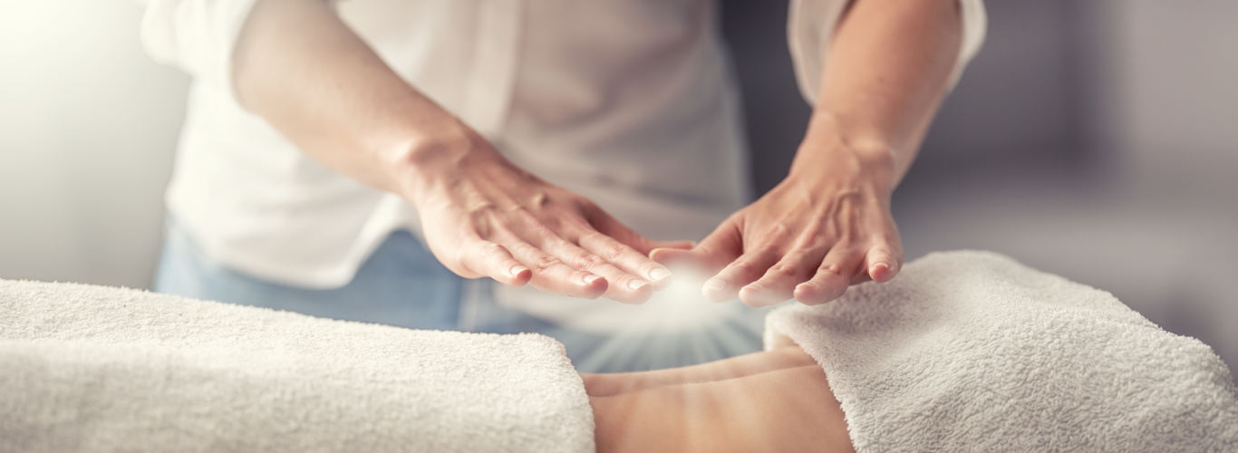 Manos terapeuta energia Reiki sobre mujer joven acostada de espaldas
